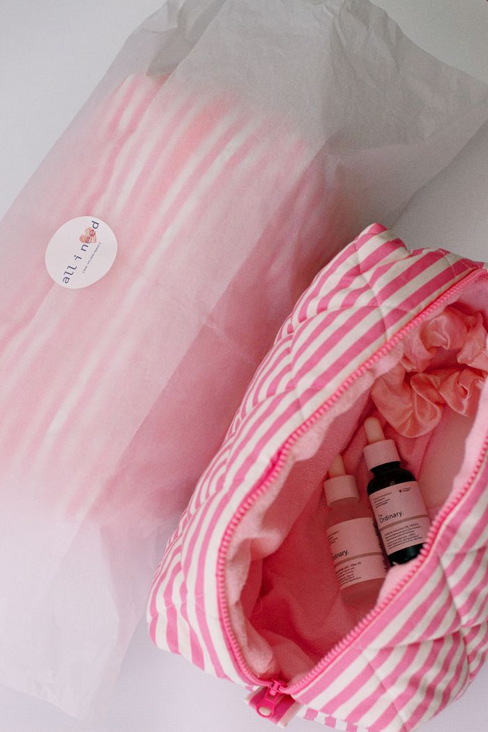 our-services-1 A top view of a pink striped cosmetic bag containing skincare products, showcasing beauty essentials.