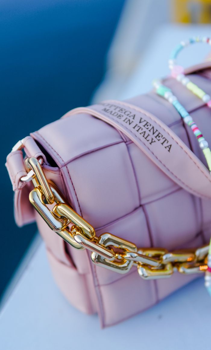 our-services-1 Close-up of a stylish pink leather shoulder bag with a gold chain detail.
