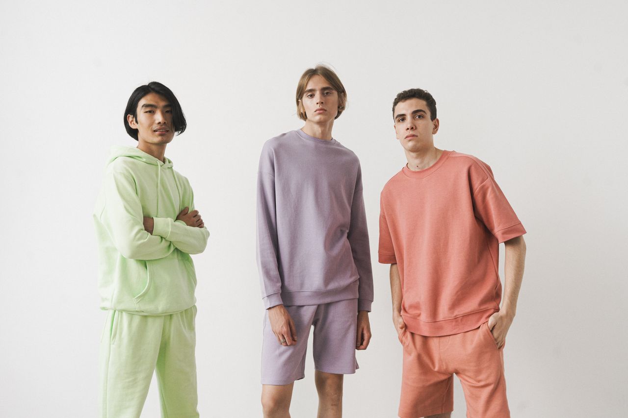 gallery-4 Three men wearing pastel loungewear poses in a studio, showcasing modern casual fashion.